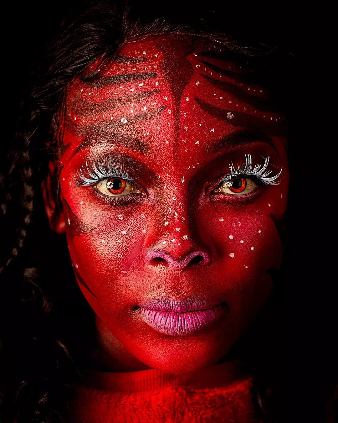 Creative portrait with red face paint and white decorative details